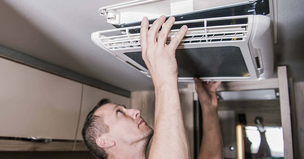 Man repairing RV air conditioning unit indoors, highlighting RV AC repair services in Colorado Springs, CO.